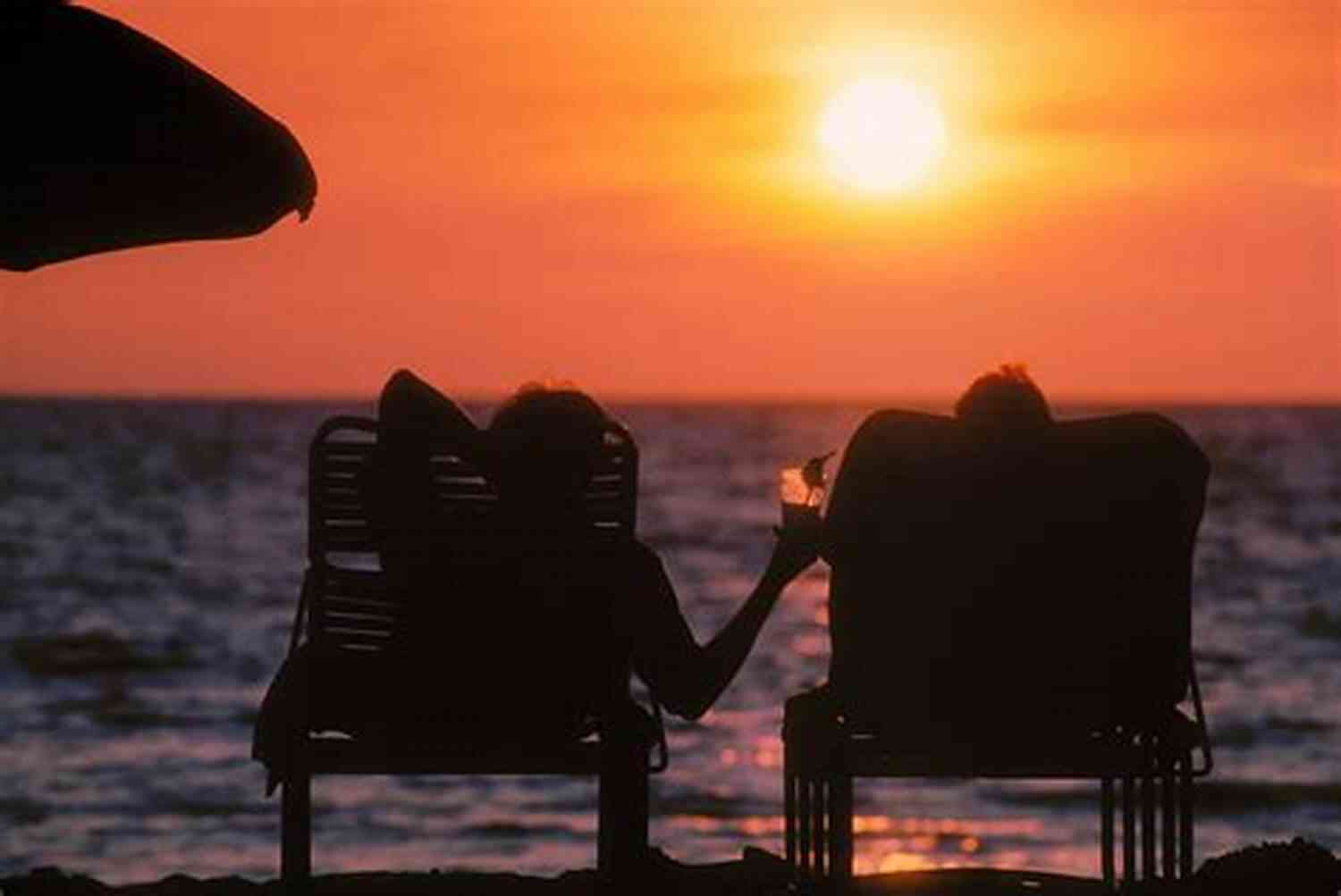 A Couple Lounging On The Beach, Wearing Sunglasses, And Sharing A Tropical Cocktail. Laugh Swoon And Fall In Love: Romance Starters