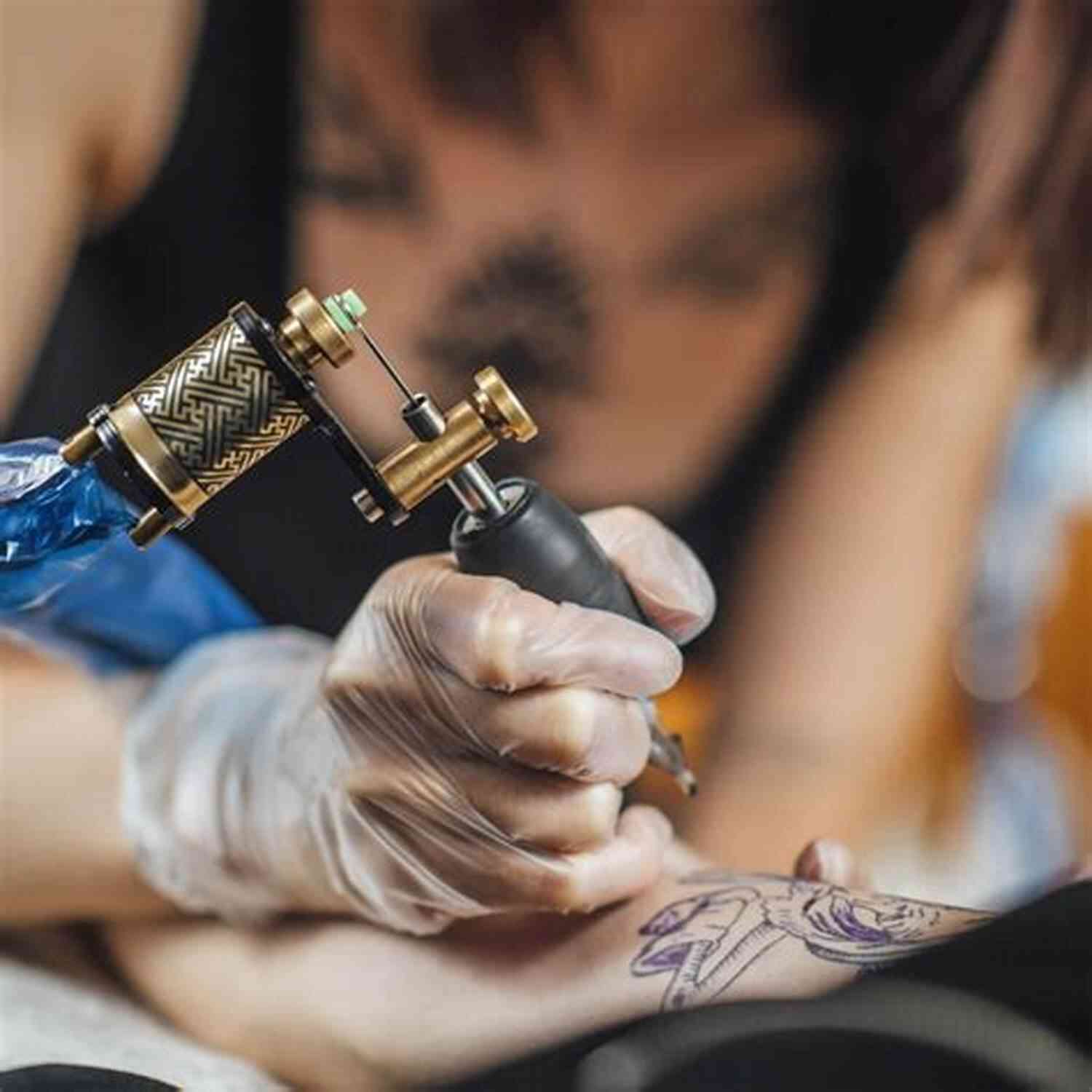 A Professional Tattoo Artist Working With A Tattoo Machine In A Studio TATTOOING HANDBOOK: The Ultimate Guide That Will Teach You The Right Way To Tattoo From Scratch